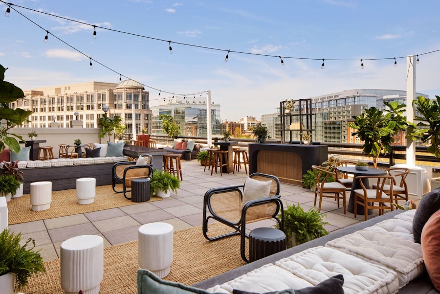 rooftop terrace with a mix of furniture, plants and string lights